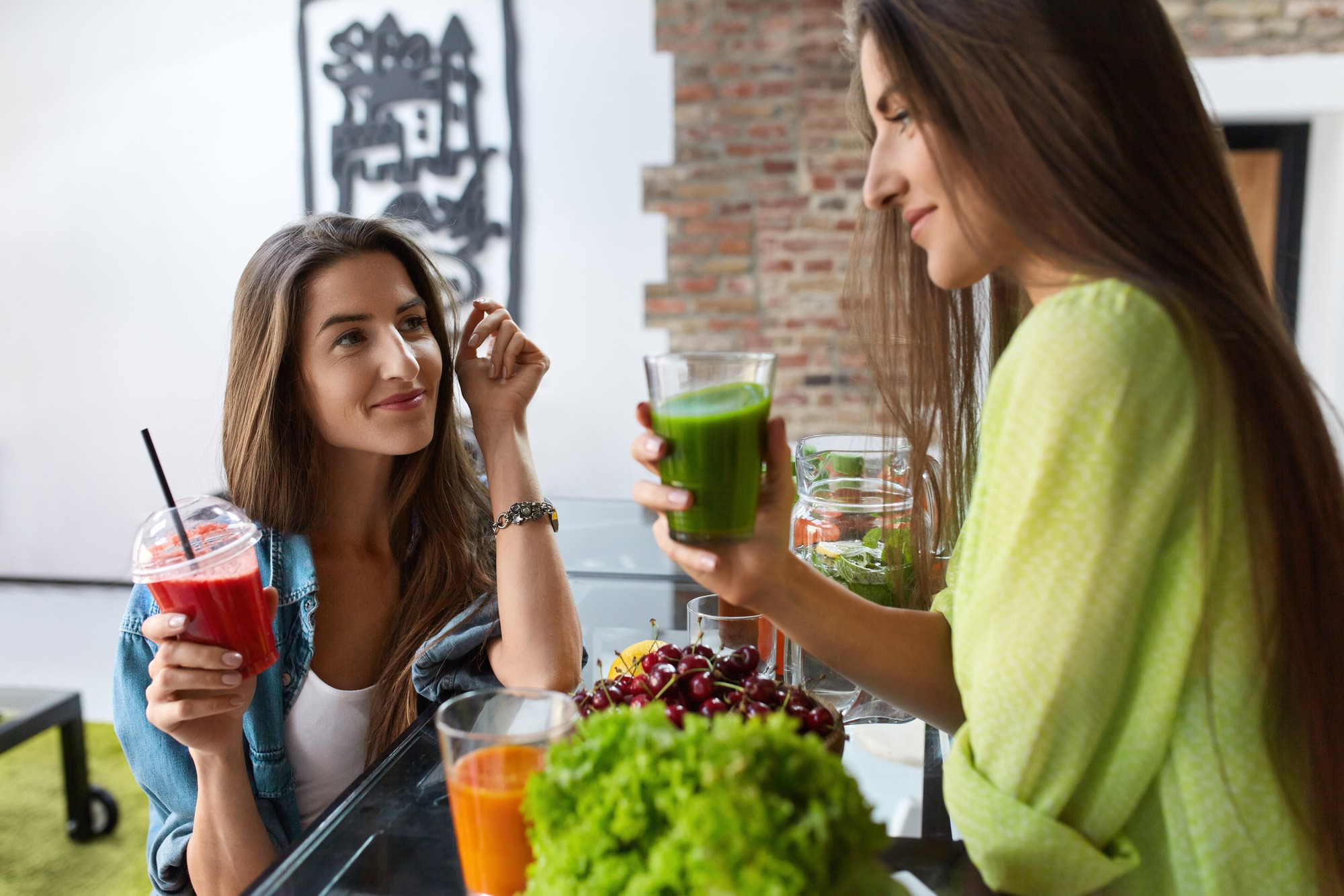 Healthy Nutrition. Beautiful Happy Women Drinking Fresh Juice, Vegetable Detox Smoothie Indoors. Fit Girls Enjoying Weight Loss Drinks Together At Home. Diet And Fitness Food Concept